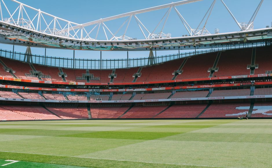 Wide-angle view of the Emirates Stadium in London showcasing its empty seats and pristine football pitch.