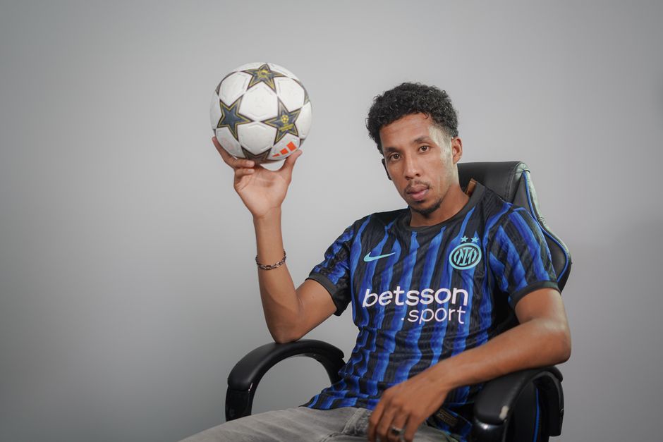 Casual portrait of a football player holding a ball indoors. Stylish and confident.